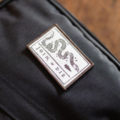 A black fabric patch with a segmented snake and “JOIN or DIE” on the Join or DIE GR1 21L - Built by Scars.