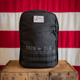The JOIN, or DIE GR1 21L - Built by Scars rests on a wooden box with a red and white flag in the background.