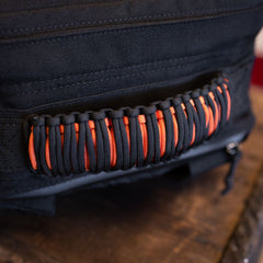 Black GR1 rucksack carry handle wrapped in black and orange paracord.