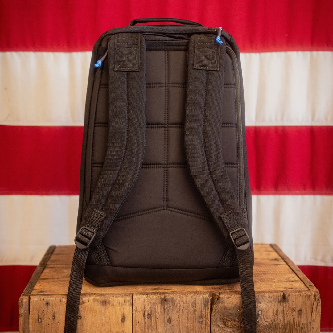 Shooter 26L Mosaic - Built by Scars sits on a crate before a red and white striped backdrop.