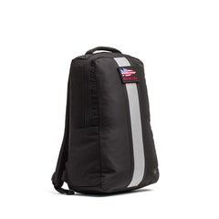 The Basic Rucker is a black backpack featuring a vertical reflective stripe and a rectangular patch on the front, designed to stand upright and comfortably fit your preferred ruck plate—making it perfect for your next rucking workout.