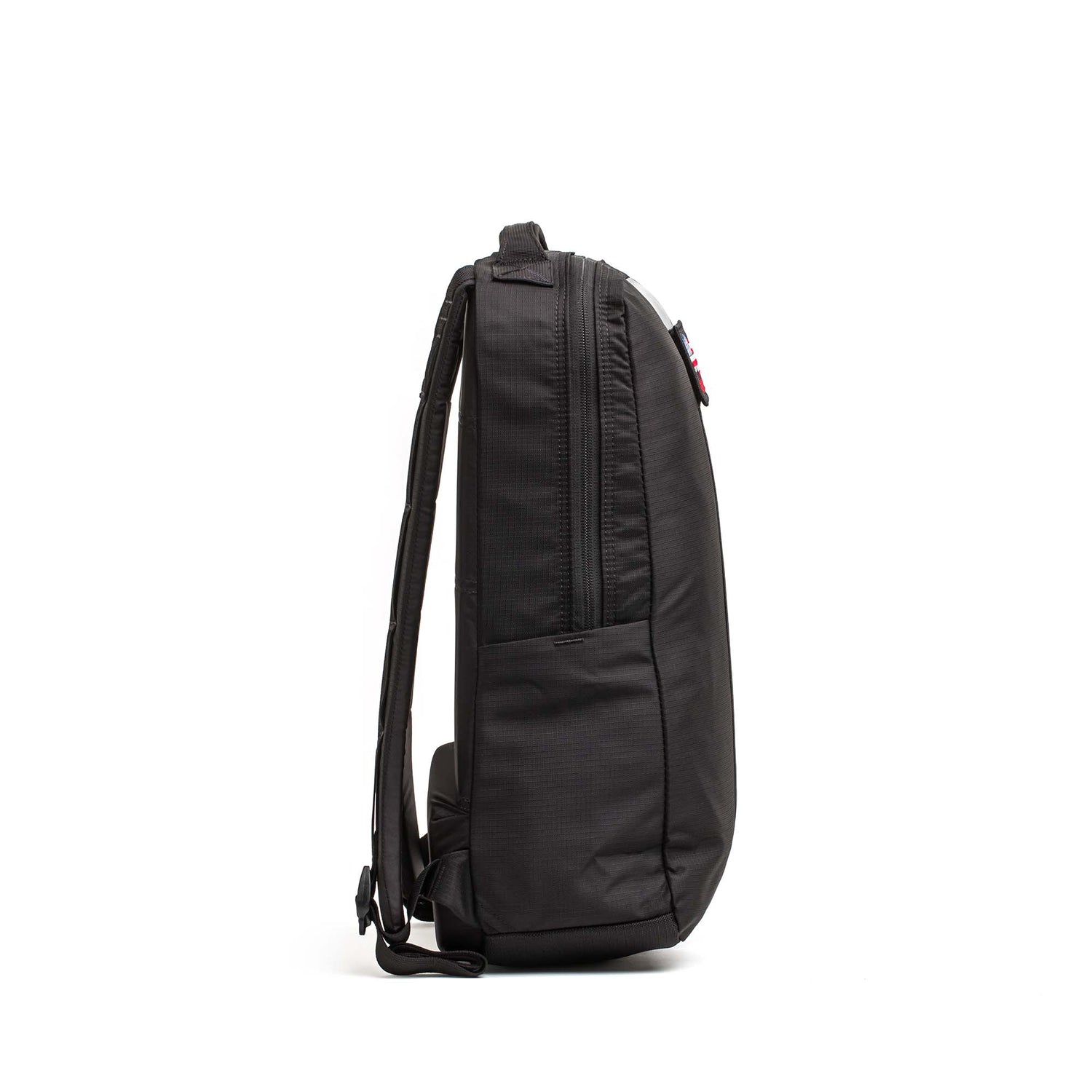 The Basic Rucker backpack in black is displayed from the side against a white background, highlighting its zipper and shoulder straps—ideal for rucking and compatible with any standard ruck plate.