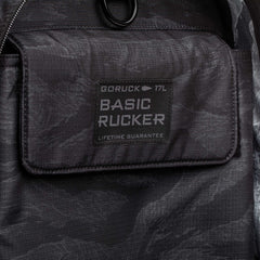 Close-up of a black Basic Rucker backpack with "GORUCK 17L BASIC RUCKER LIFETIME GUARANTEE" labeled on the front pocket.