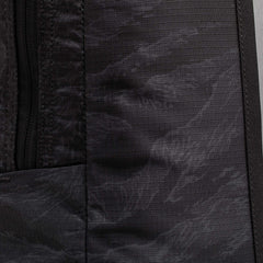 Close-up of the Basic Rucker's black textured fabric with a left-side zipper, highlighting the backpack's durable material.