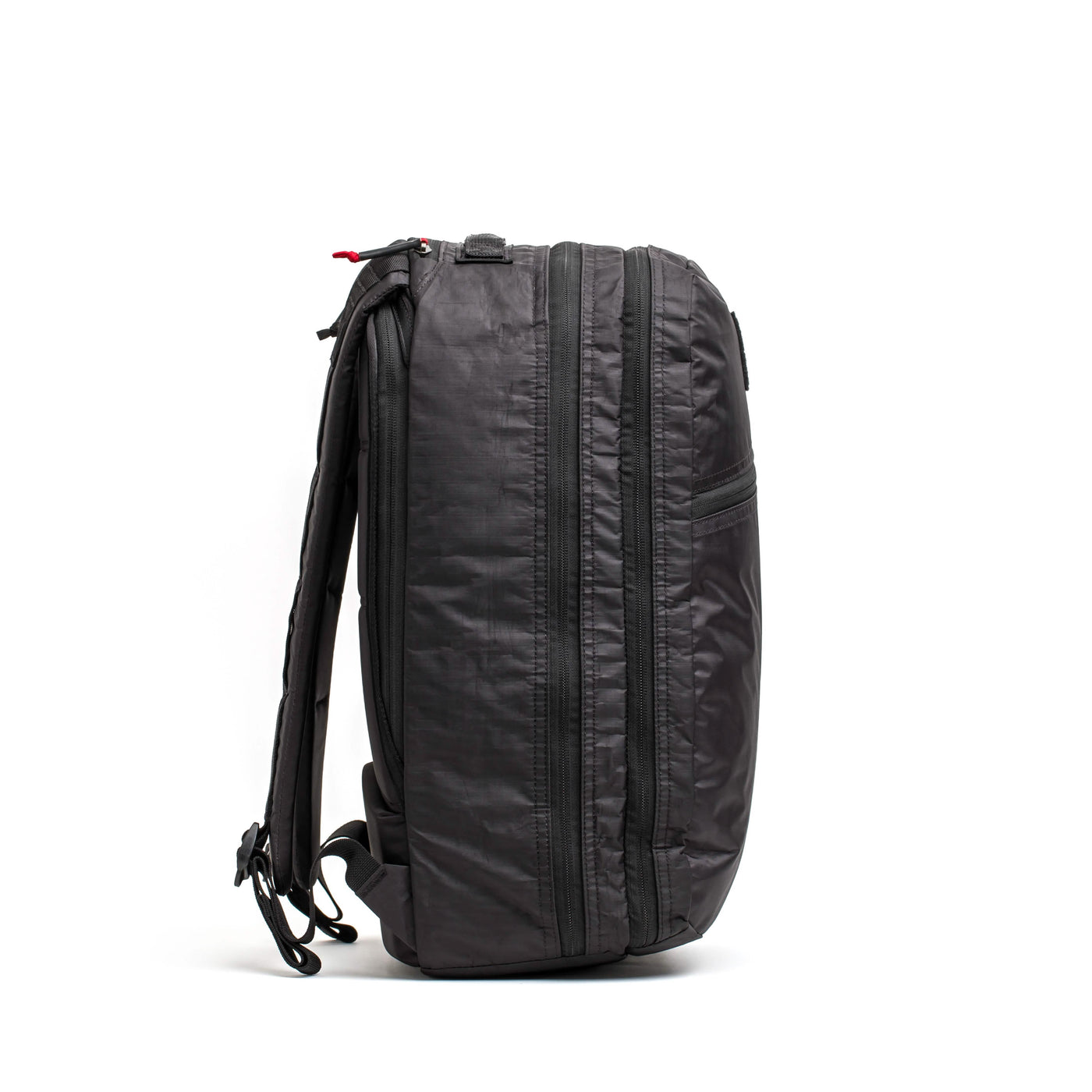 The GORUCK Bullet Ruck Double Compartment, made from durable Dyneema, is displayed in profile against a white background. It boasts a sleek design with multiple zippers, adjustable shoulder straps, and a sturdy top handle, all backed by a lifetime guarantee for enduring quality.