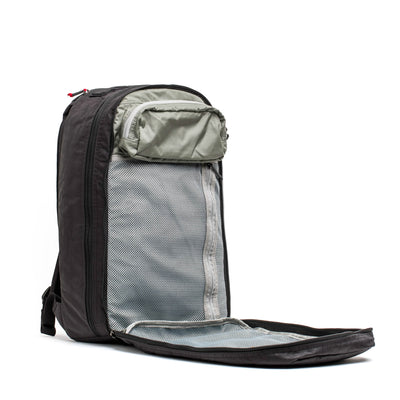A GORUCK Bullet Ruck Double Compartment in black is open, showcasing its main section lined with a gray mesh pocket along with an extra small zippered pocket inside. Constructed from robust Dyneema fabric, it features a sleek, contemporary design equipped with a visible zipper and adjustable straps, all supported by a lifetime guarantee.