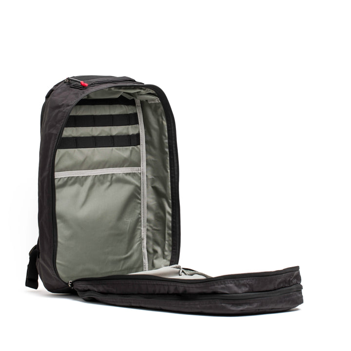 The Bullet Ruck Double Compartment - Dyneema by GORUCK, an open black backpack, features a spacious main compartment and multiple interior pockets lined with grey fabric. Set against a plain white background, this durable bag highlights its organizational attributes and minimalist design while providing a lifetime guarantee.