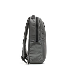 The Basic Rucker® in gray is shown from the side, featuring padded straps and a front zip pocket for convenient storage.