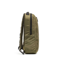 Side view of an olive green Basic Rucker® with black zippers and adjustable shoulder straps, set against white—a durable backpack designed for weighted training or everyday carry.