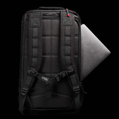 The GR2 by GORUCK, displayed against a black background, exemplifies Special Forces quality with its padded straps and a partially visible laptop in the side compartment. A small red detail provides contrast to the design, and it is carry-on compliant for convenient travel.