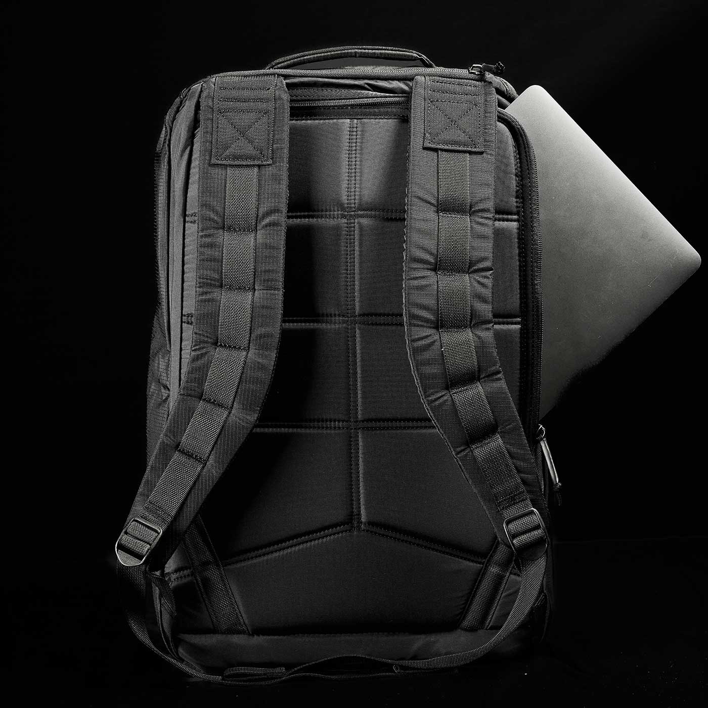 A black backpack with padded straps and a laptop partially visible in its back compartment.