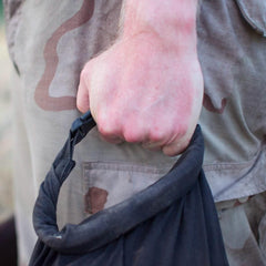 Hand gripping GORUCK rucking gear handle, close-up against tactical pants outdoors