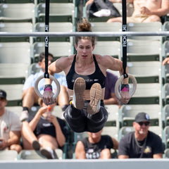 Athlete wearing GORUCK gear performing ring muscle-up at outdoor fitness event