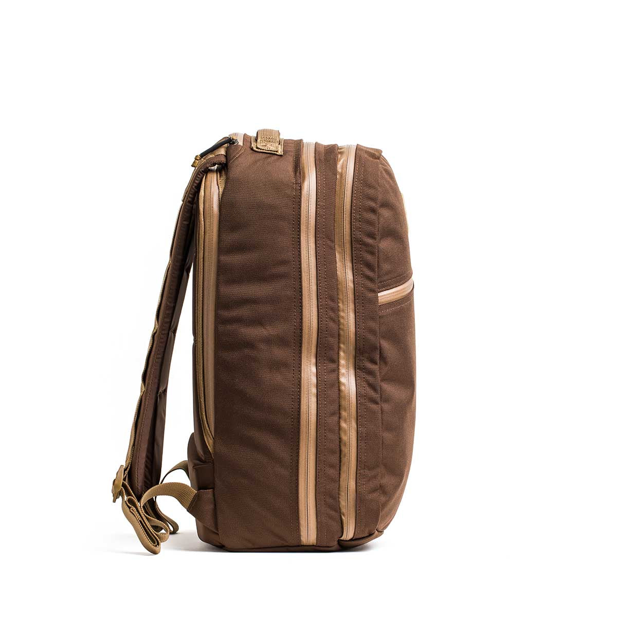 Side view of the brown Double Bullet Ruck w/ Bombproof Laptop Compartment - 18L, featuring tan zippers, padded shoulder straps, and a bombproof laptop compartment, shown against a white background.