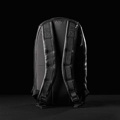 Back view of black leather GORUCK Bullet 15L backpack with padded straps on black background