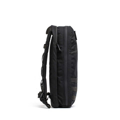 The Bullet Ruck USA Throwback is a sleek black daypack with visible zippers, an adjustable shoulder strap, and durable CORDURA construction, shown from the side.