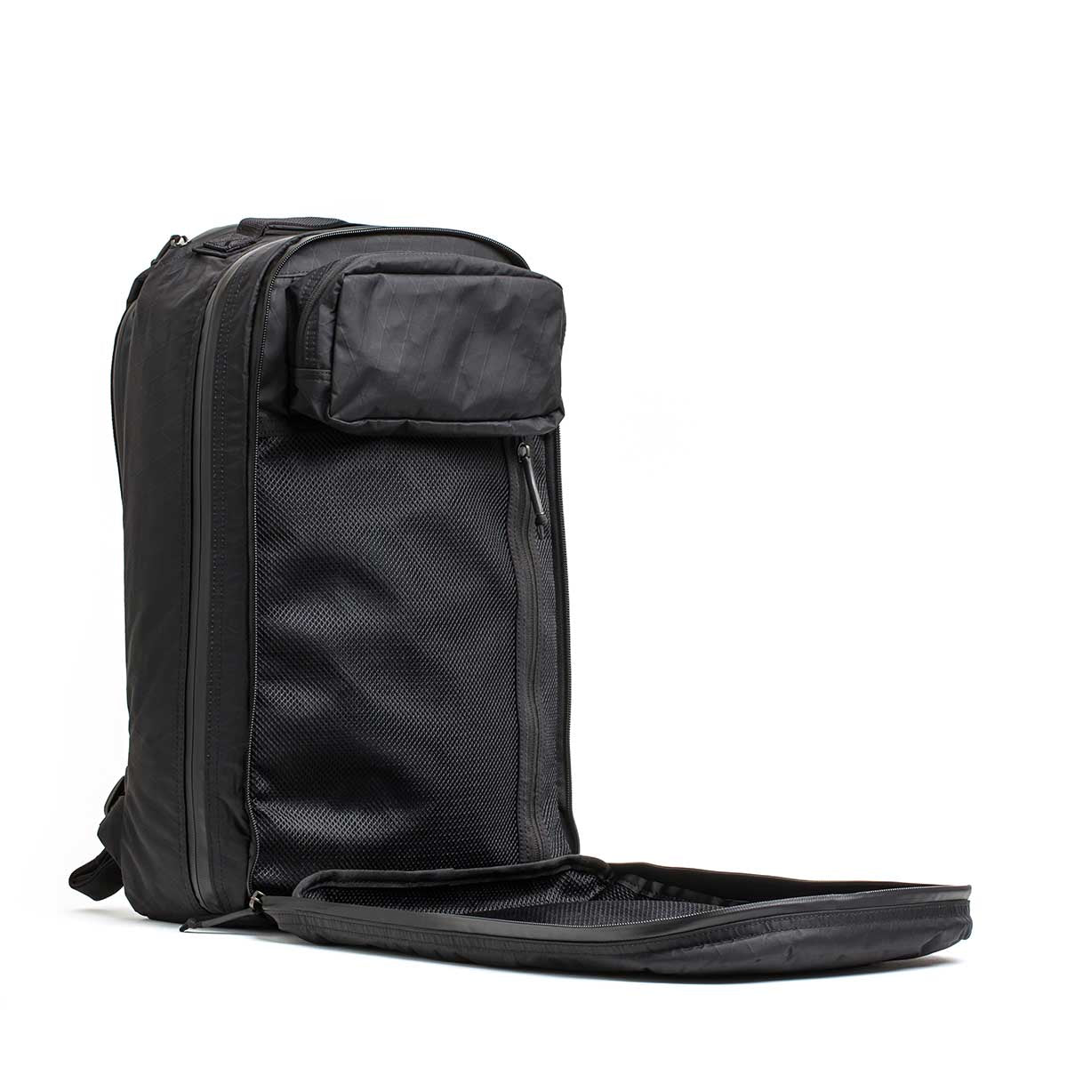 The Double Compartment Bullet Ruck - XPAC stands upright with its front compartment unzipped, revealing mesh pockets. It features a bombproof laptop compartment for ultimate protection while traveling.