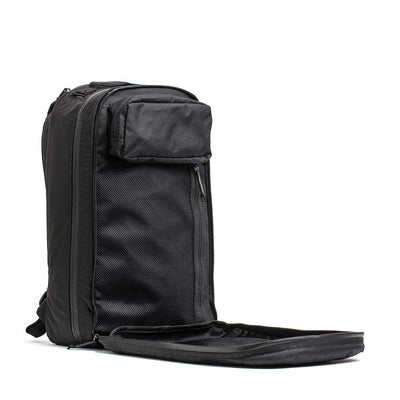 The Double Compartment Bullet Ruck - XPAC stands upright with its front compartment unzipped, revealing mesh pockets. It features a bombproof laptop compartment for ultimate protection while traveling.