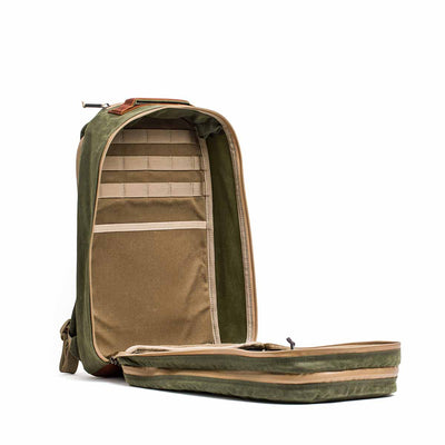 The Waxed Canvas 18L Bullet Ruck is a green and brown backpack with dual compartments and multiple zippers on a white background. It offers rugged durability backed by Scars Lifetime Guarantee, ensuring it withstands every adventure.