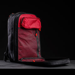 The Bullet Ruck x Carryology - GRXC2 Samurai 2.0 backpack is fully unzipped, revealing red mesh and fabric pockets against a black background, with limited-edition JPXDP 17oz Black Samurai Sashiko accents for a unique touch.