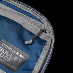 Close-up of a blue and gray daypack featuring a "Bullet Ruck Classic - Cordura" patch and zipper detail, crafted from durable Cordura fabric.