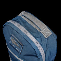 The Bullet Ruck Classic - Cordura backpack is blue with gray zippers and a logo on the front pocket, all set against a black background with a streamlined design.