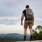 Man rucking in GORUCK shorts and camo backpack overlooking scenic outdoor landscape