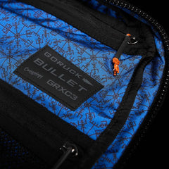 Close-up of blue interior lining with black geometric patterns inside a GORUCK Bullet backpack, featuring Carryology GRXG3 label and zipper pull
