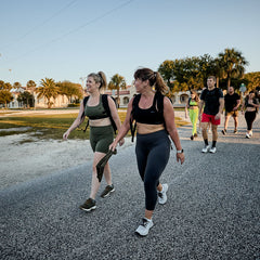 Group of fit men and women rucking outdoors during sunset wearing athletic gear and backpacks on a suburban street