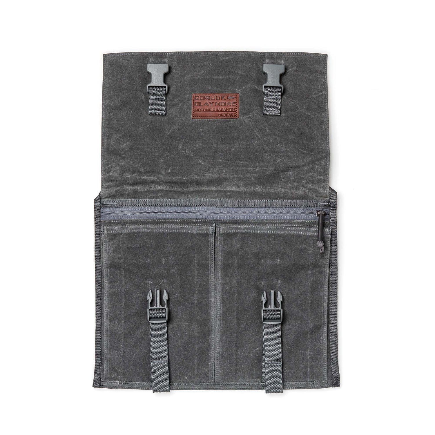 The Waxed Canvas Claymore Sling Bag, featuring buckles, zippers, and a leather patch, is displayed flat on a white background.