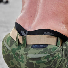 Close-up of a person wearing camo GORUCK pants with tan belt, sweaty lower back visible
