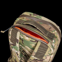Close-up of camouflage GORUCK 15L Bullet backpack with orange interior and rugged handle on black background