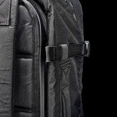 Close-up of the black GR3 - X-PAC carry-on backpack, showing a strap with buckle against a black background. Made from waterproof material and protected by the Scars Lifetime Guarantee for lasting durability.