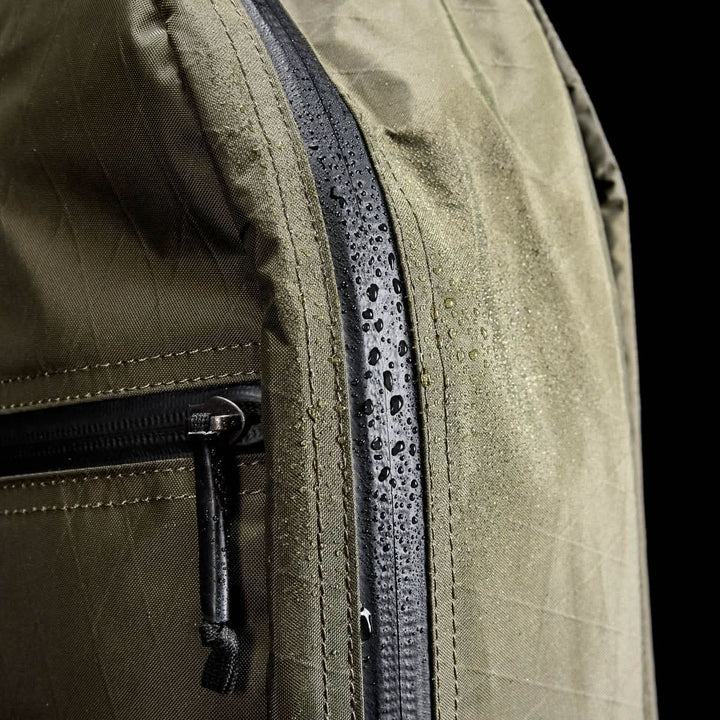 Close-up of the Bullet X-PAC daypack with water droplets on its X-PAC fabric and AquaGuard zippers, showcasing its waterproof design.
