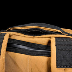 Close-up of tan GORUCK rucksack with black straps and padded handle detail
