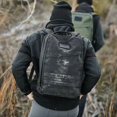 Hiker wearing black tactical jacket and beanie with dusty black GORUCK rucksack on rugged outdoor trail