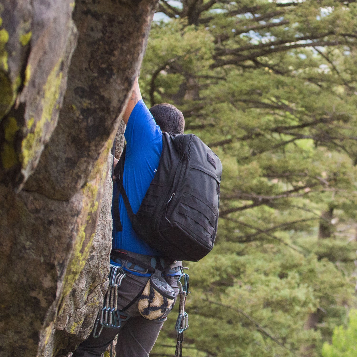 A person rock climbing outdoors with the GR2 USA - Cordura backpack, surrounded by trees and equipped with climbing gear.