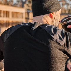 Man wearing black beanie and black long-sleeve shirt with reinforced shoulders outdoors