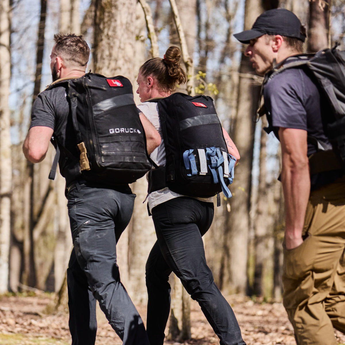 Three people wearing backpacks and fast-drying technical ToughDry pants hike along a wooded trail.