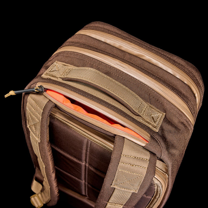 The Bullet Ruck - Ballistic Nylon Cordura - 18L, in brown and tan with an orange interior and bombproof laptop compartment, is displayed from above against a black background.
