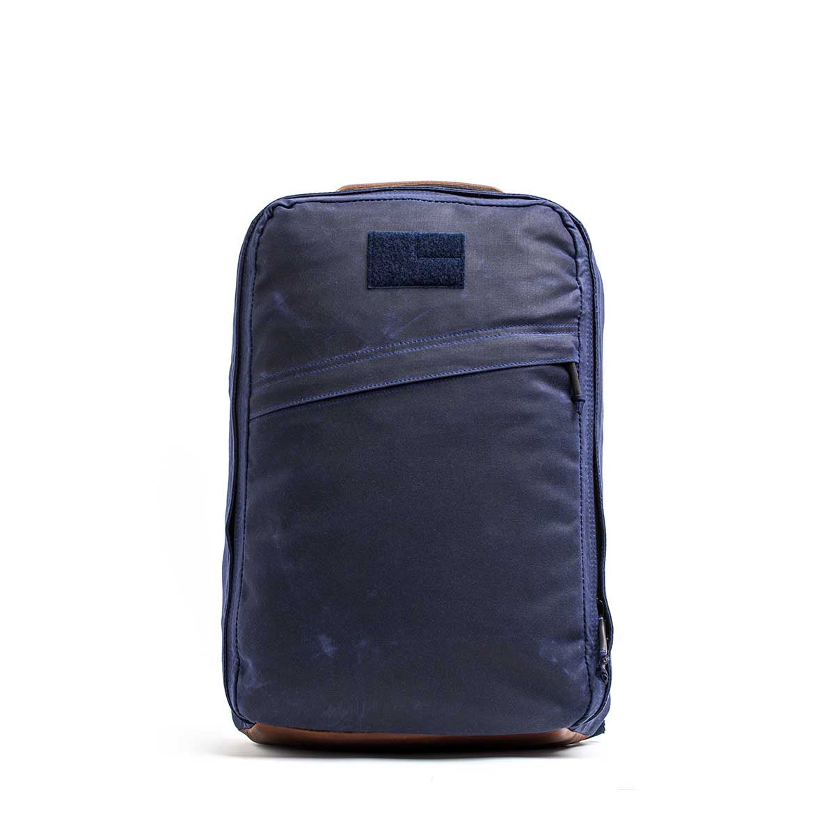 The GR1 USA - Heritage Waxed Canvas is a navy blue rucksack with a front zipper pocket, shown against a plain white background.
