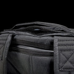 Close-up of black tactical rucksack strap and zipper details with durable stitching on black fabric
