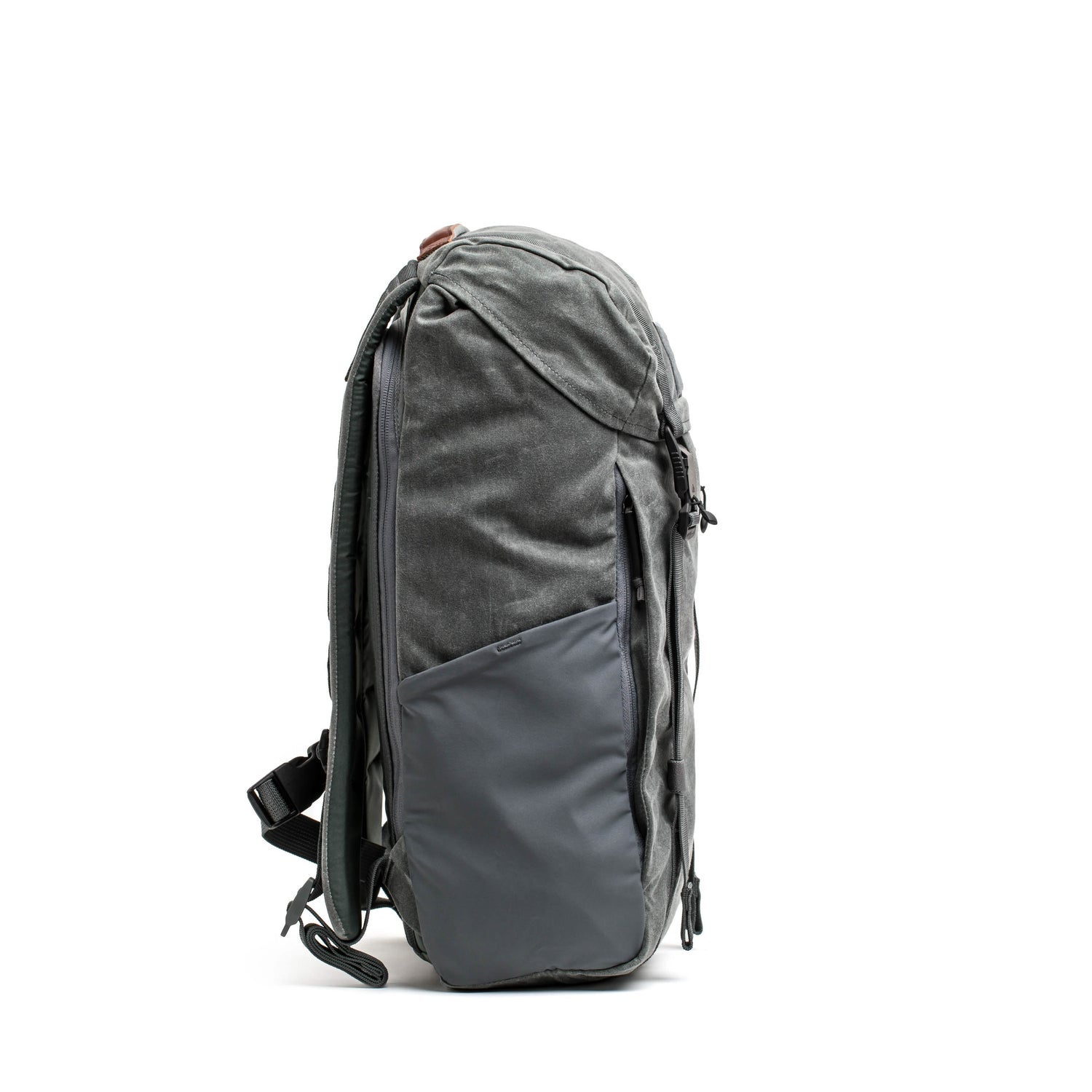 The M24 - Waxed Canvas from GORUCK features a streamlined design with multiple compartments, constructed from robust materials. Positioned upright on a plain white backdrop, it includes an ergonomic shoulder strap and a zippered front pocket.