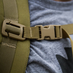 Close-up of the Training Sternum Strap's adjustable rucksack strap with a plastic buckle, shown on a person wearing a gray shirt.