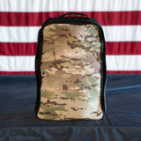 GORUCK camo rucksack on dark surface in front of American flag backdrop