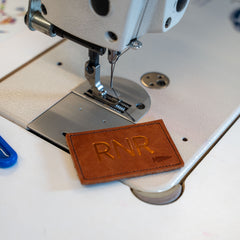 A Patch - Custom Leather Monogram with "RNR" engraved sits on a sewing machine work surface.