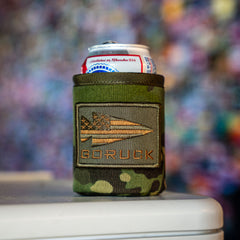 A can of Pabst Blue Ribbon beer in a Ballistic Beer Jacket by GORUCK, featuring camouflage material and an arrow and flag patch.