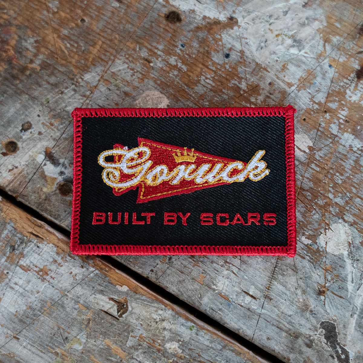 The Scrap Shooter is a rectangular patch displayed on a wood surface, crafted from Special Forces grade CORDURA—ideal for your GR1 backpack.