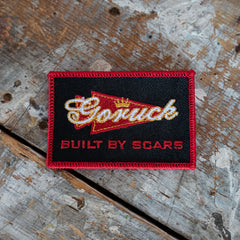 The Scrap Shooter is a rectangular patch displayed on a wood surface, crafted from Special Forces grade CORDURA—ideal for your GR1 backpack.
