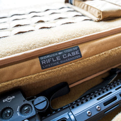 Close-up of a tan Rifle Case with a visible label and part of a rifle featuring an EOTech sight.